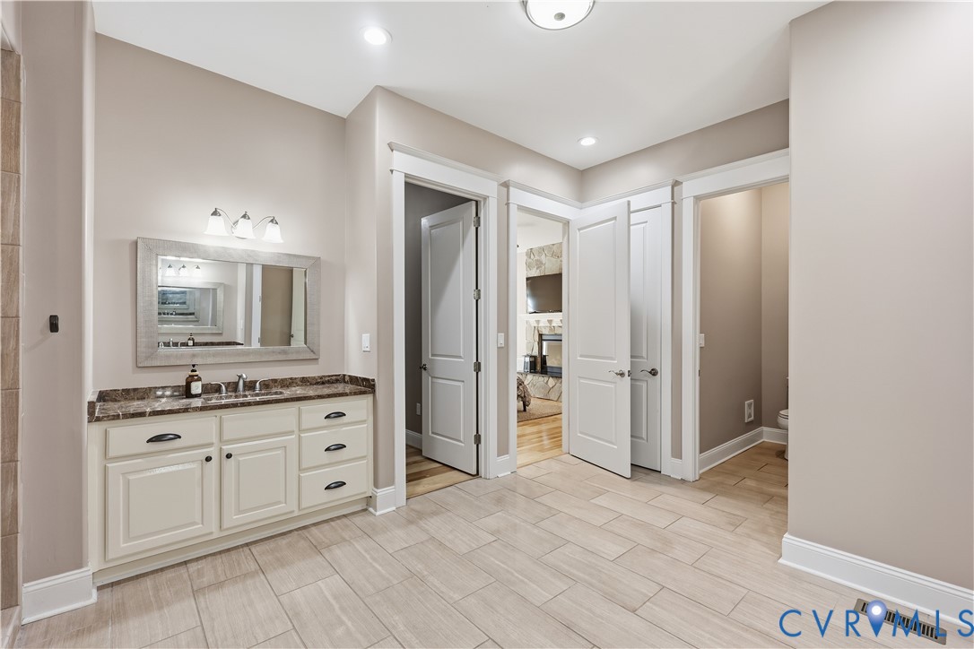 Primary Bathroom 2 featuring a vanity with neutral cabinetry, a stone-finish countertop, a rectangular framed mirror, inset panel doors, and tile flooring