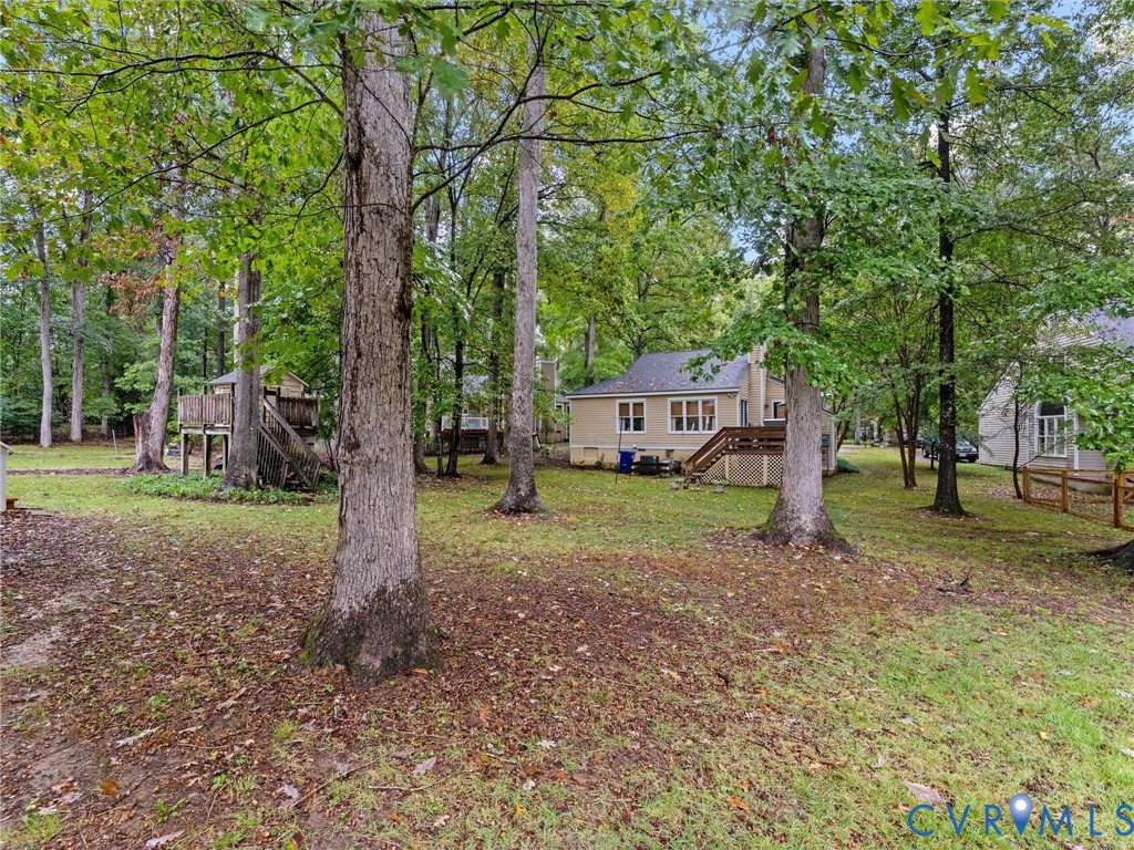 Expansive backyard featuring mature trees, an elevated wooden deck, and a detached wooden structure