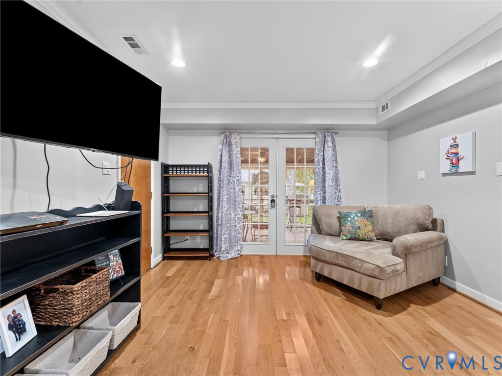 Wood-finish flooring, recessed lighting, crown molding, and glass-paneled double doors