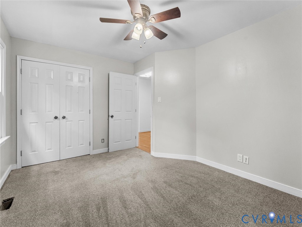Neutral-toned carpeting, ceiling-mounted light fixture with multi-blade fan, six-panel closet doors, and interior passage door