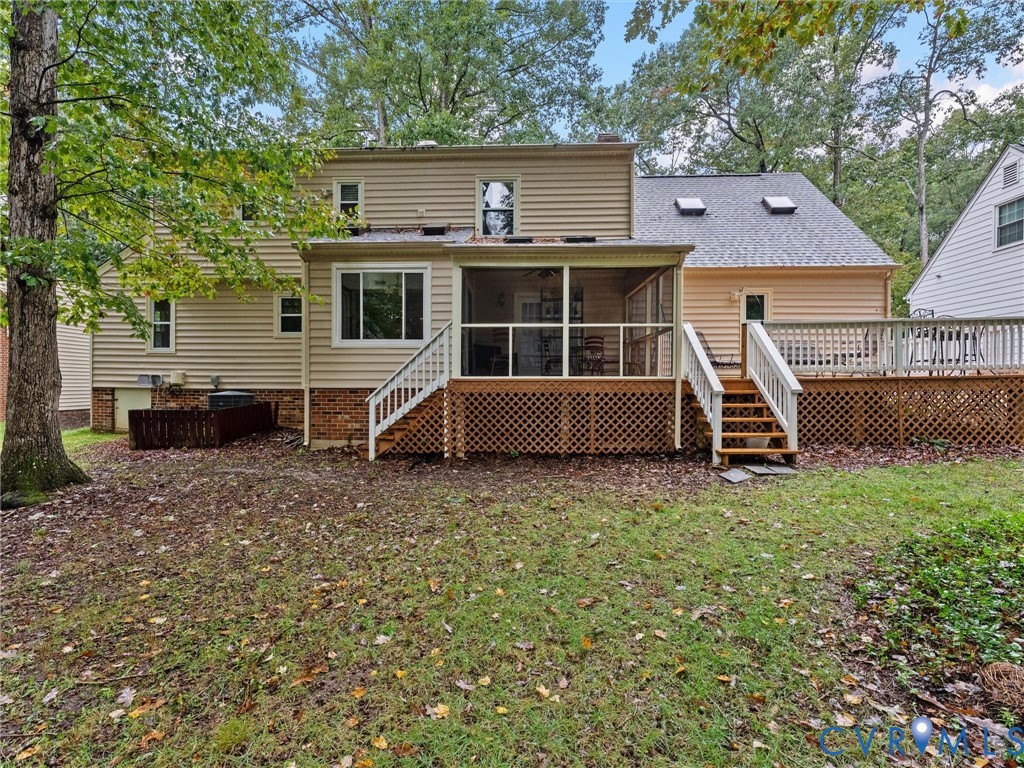 Rear exterior featuring vinyl siding, a screened-in porch with wood-style decking, an expansive open deck with lattice skirting, and two roof-mounted skylights