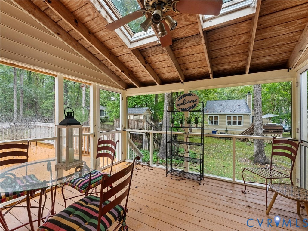 Screened porch featuring exposed wood-beam vaulted ceilings, two integrated skylights, wood-finish decking, and white structural framing