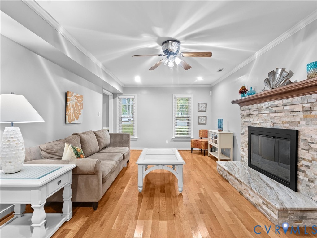 Living area featuring wood-finish flooring, vaulted ceilings, and a stacked-stone fireplace with a natural stone hearth and wood mantel