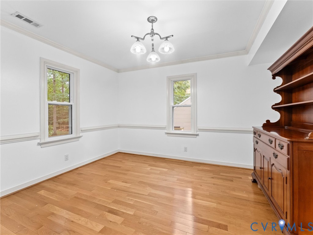 Wood-finish flooring, crown molding, chair rail trim, dual-pane windows, and three-light brushed-nickel chandelier