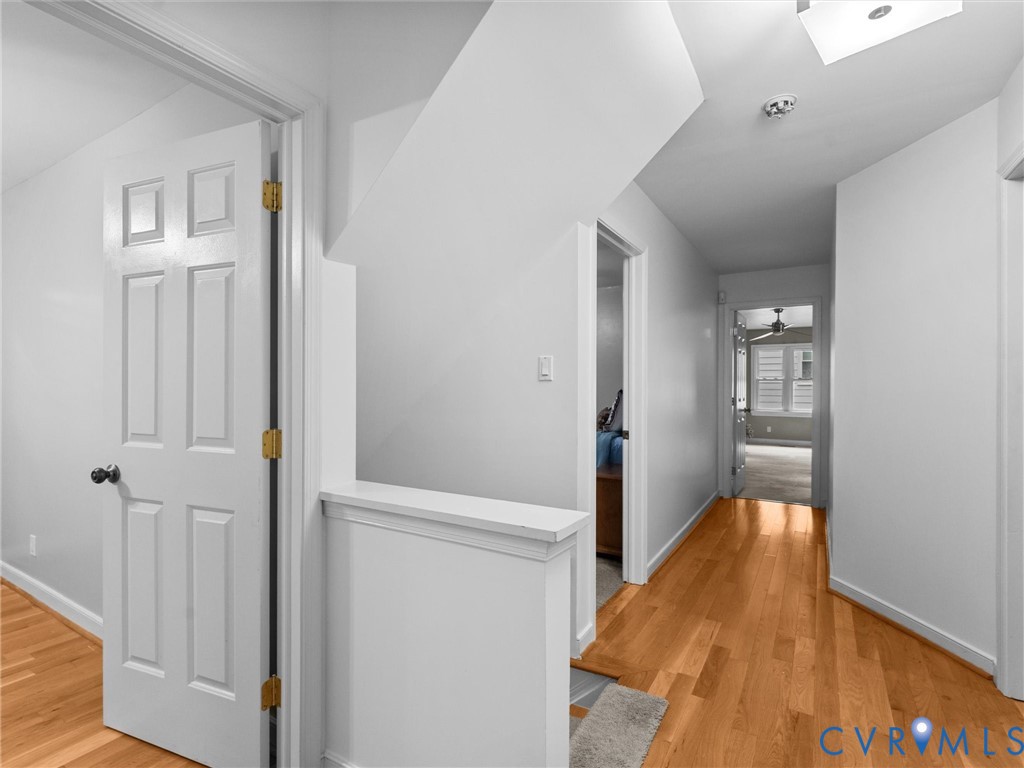 Hallway featuring wood-finish flooring, six-panel interior doors, and a capped half-wall