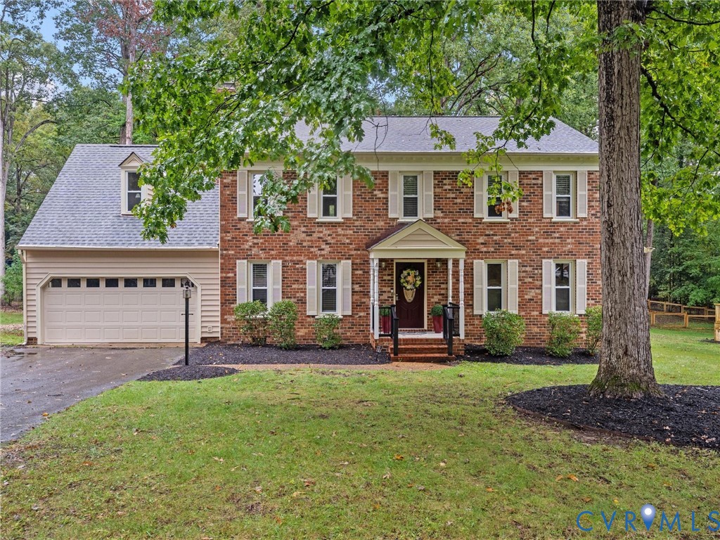Two-story brick exterior featuring a multi-paned front door, decorative shutters, an attached two-car garage, and a covered front entryway