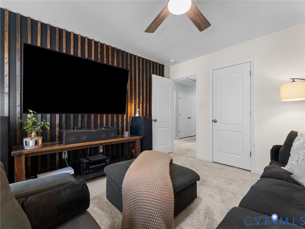 Accent wall featuring vertical wood slat paneling, carpeted flooring, two-panel interior doors, and a ceiling-mounted fan with light fixture