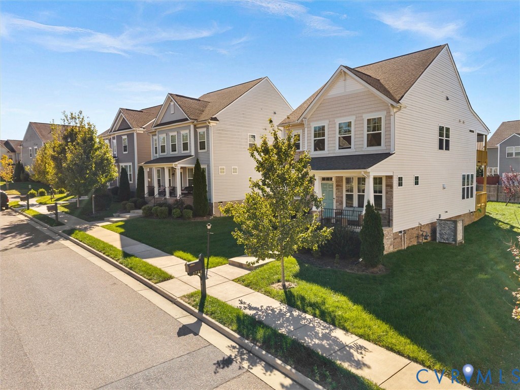 Two-story residence featuring light-toned vinyl siding, stone masonry accents, a covered front porch, and a dedicated concrete driveway