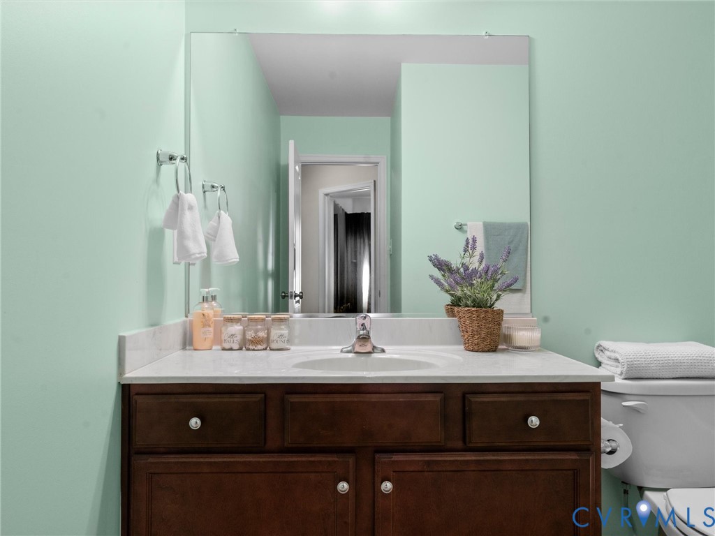 Dark wood cabinetry vanity featuring a stone countertop, integrated sink, polished chrome faucet, and a wall-mounted mirror