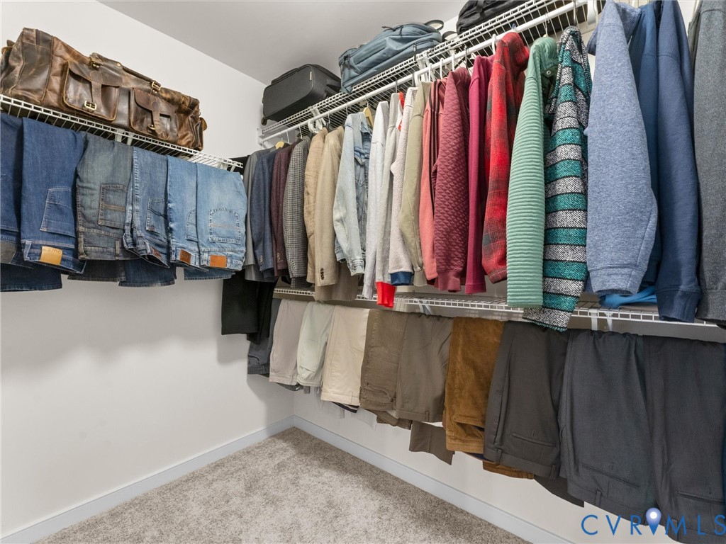 Walk-in closet featuring tiered wire shelving and neutral-toned carpeting