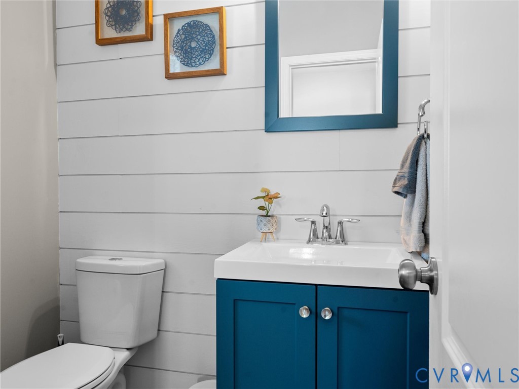 Bathroom featuring horizontal shiplap wall paneling, a blue vanity cabinet with a white basin, a polished chrome centerset faucet, and a matching framed wall mirror
