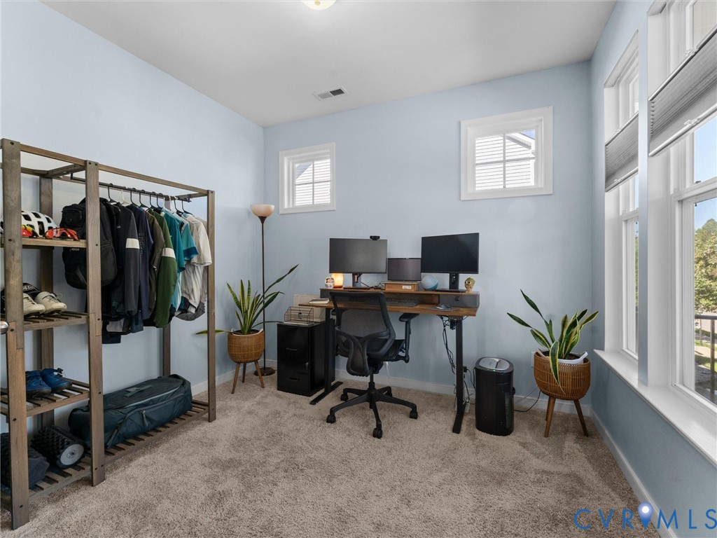 Room featuring neutral-toned carpeting, dual-pane windows with white trim, and light blue wall finish