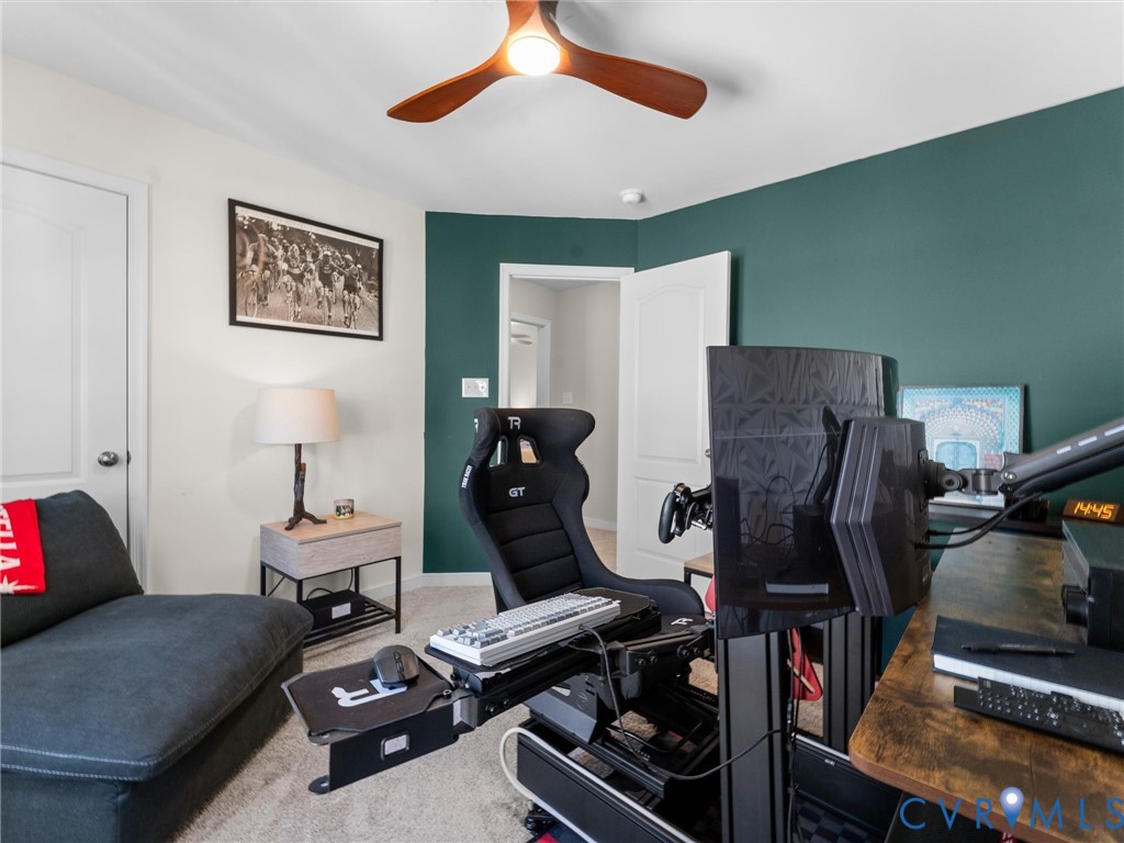 Three-blade wood-finish ceiling fan with integrated lighting, neutral wall-to-wall carpeting, and an accent wall painted in a deep forest green