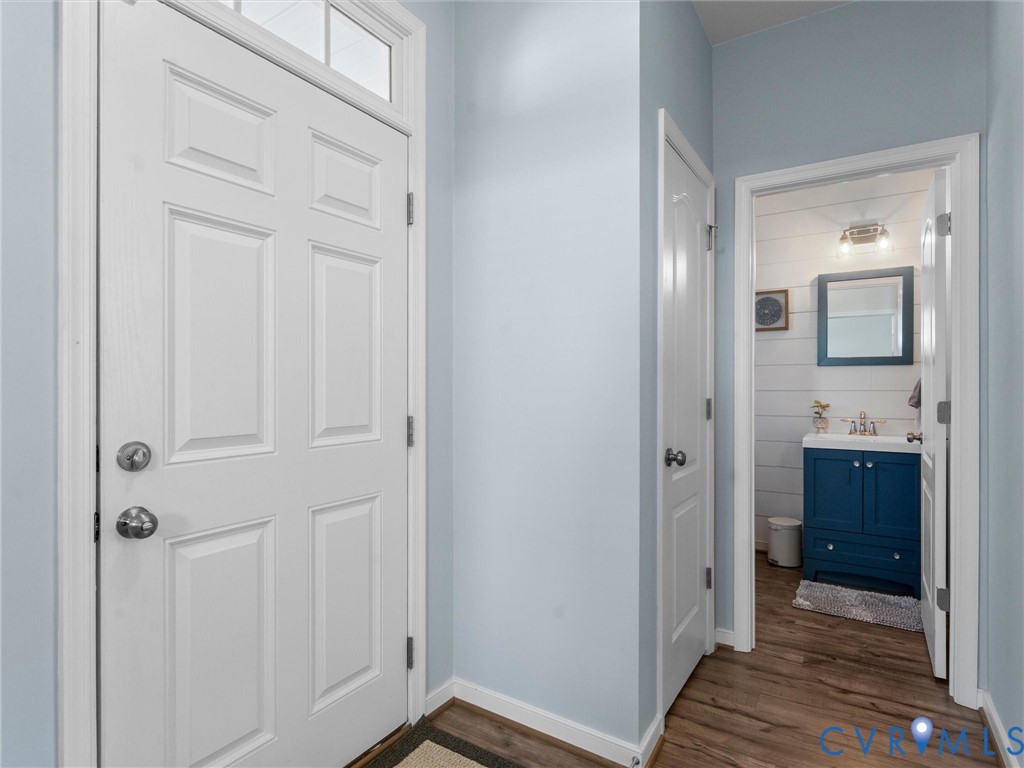 Entryway featuring a white paneled door with transom window and wood-finish flooring