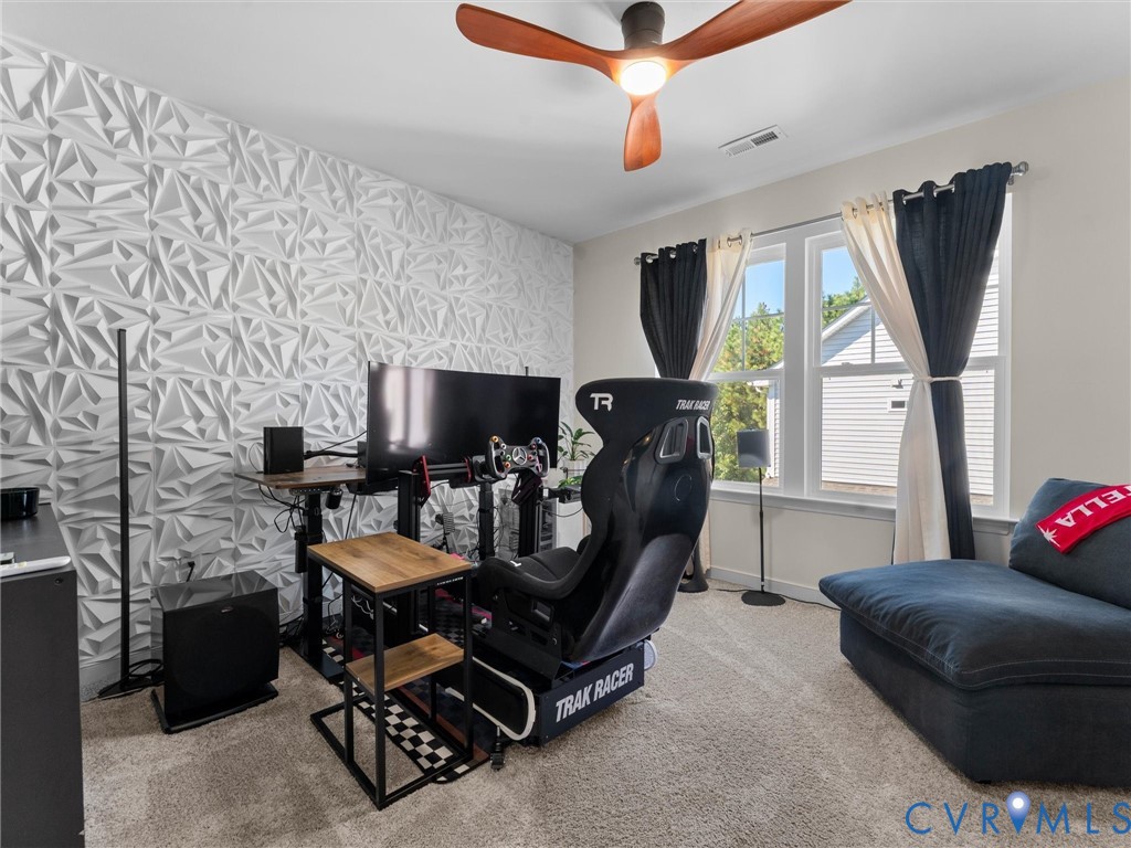Textured three-dimensional accent wall, large windows with natural light, and contemporary wood-finish ceiling fan