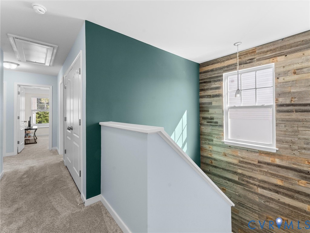 Hallway featuring an accent wall with wood-finish paneling, a secondary deep-toned accent wall, and a single-light pendant fixture
