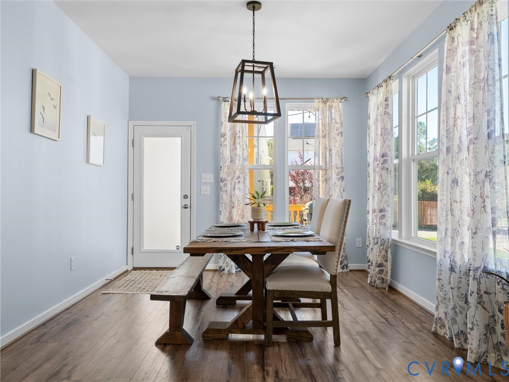 Dining area featuring wood-finish flooring, a geometric metal pendant light fixture, and multiple large windows