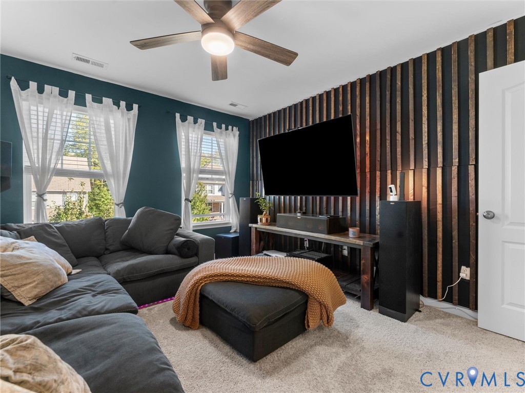 Room featuring a vertical wood-slat accent wall, dual windows, and a ceiling fan with integrated lighting