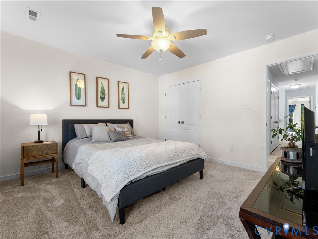 Neutral wall tones, carpeting, ceiling fan with integrated lighting, and double-door closet storage