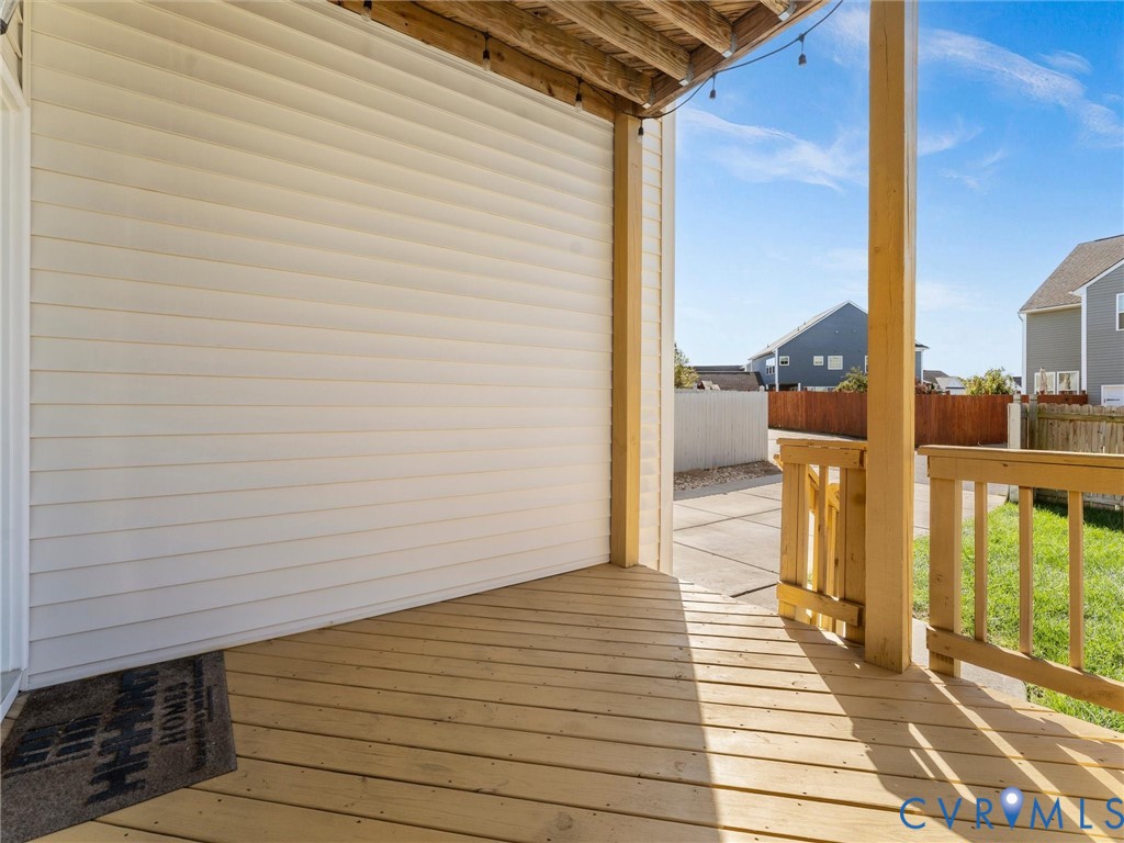 Covered wooden deck featuring horizontal siding, natural wood support posts, and wooden railing