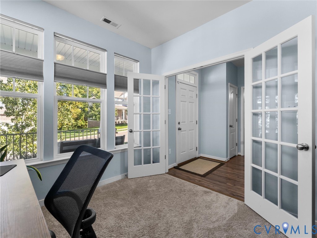 Multi-pane French doors, wall-to-wall carpeting, and triple window configuration featuring integrated cellular shades
