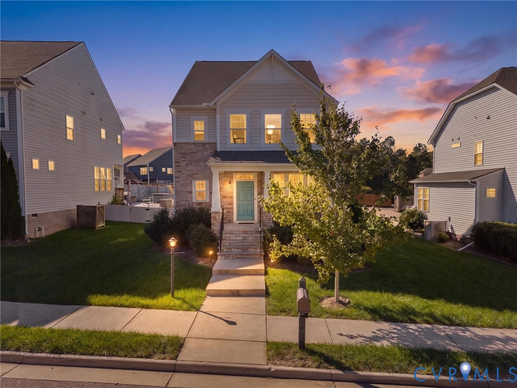 Two-story residence with mixed siding and stone veneer exterior, covered front porch with column supports, and concrete entryway stairs Two-story residence with mixed siding and stone veneer exterior, covered front porch with column supports, and concrete entryway stairs