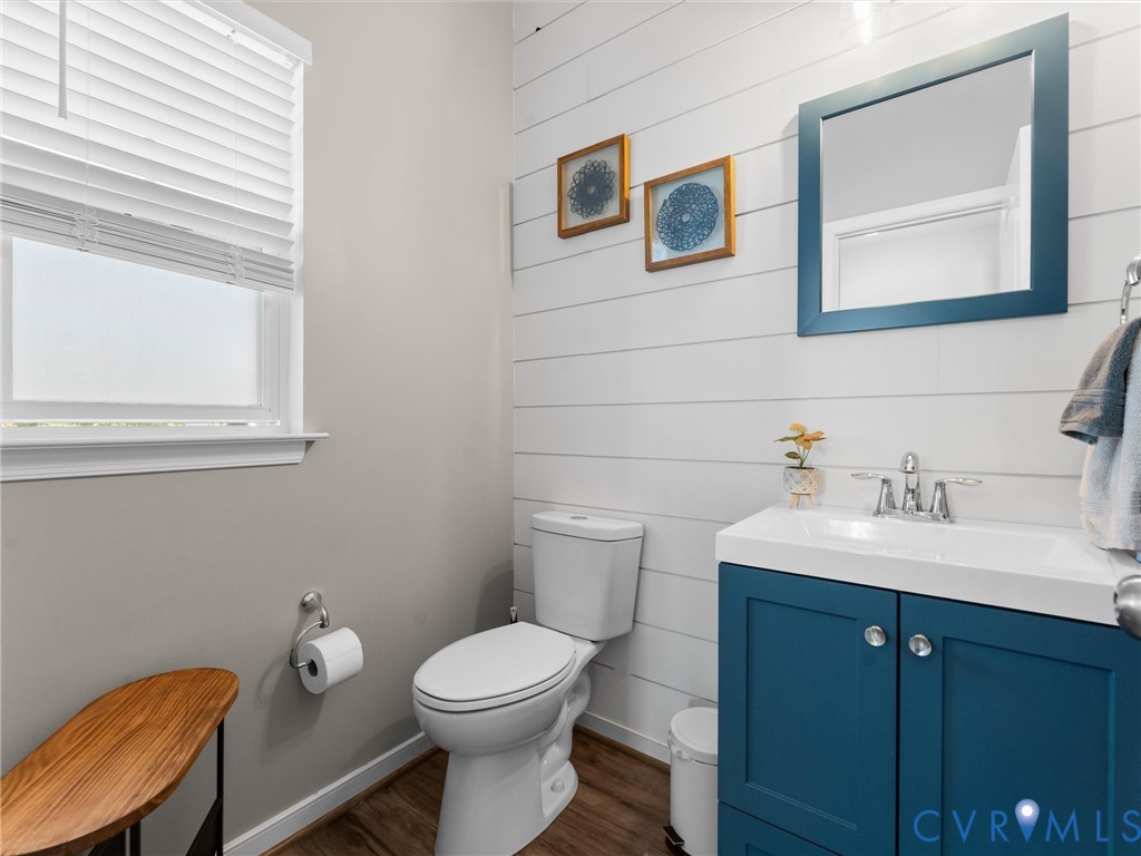 Horizontal plank wall paneling, deep-toned blue vanity cabinet with a crisp white basin, polished chrome faucet, and wood-finish flooring