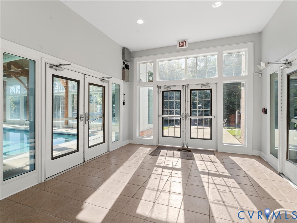 Ceramic tile flooring, multiple sets of white-framed glass paneled doors, recessed lighting, and extensive window transoms
