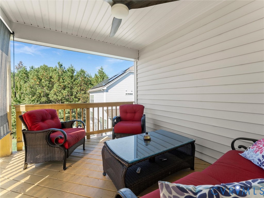 Covered deck featuring horizontal siding, wood-plank flooring, and a ceiling-mounted fan