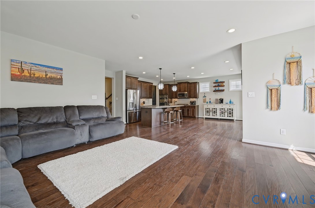 Open-concept interior featuring wood-finish flooring, recessed lighting, and a kitchen island with pendant lighting Open-concept interior featuring wood-finish flooring, recessed lighting, and a kitchen island with pendant lighting
