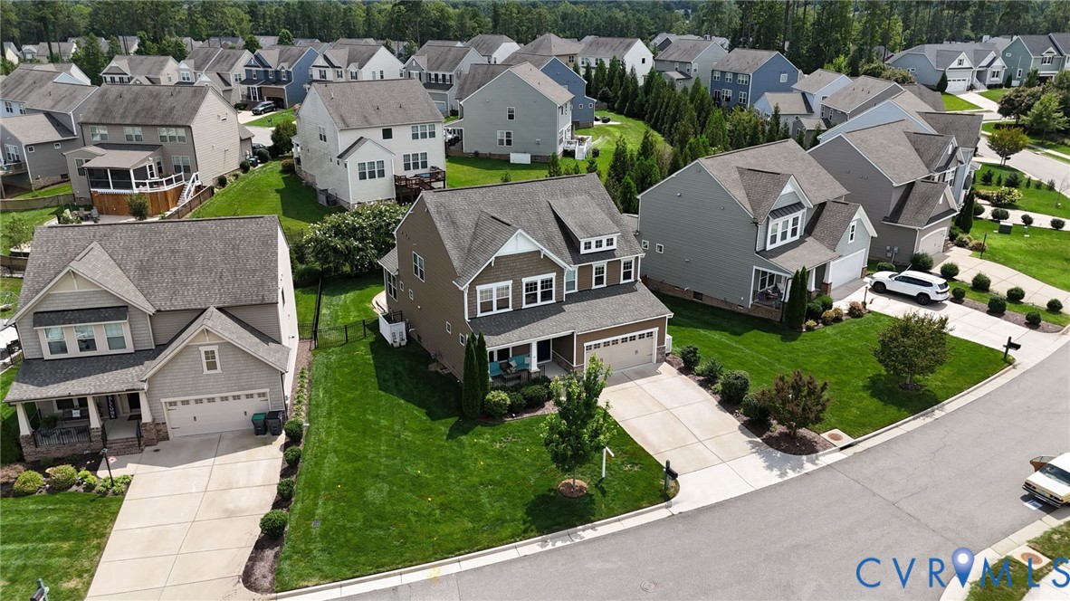 Aerial perspective of a two-story residence featuring a front-facing attached two-car garage, concrete driveway, and expansive lawn area