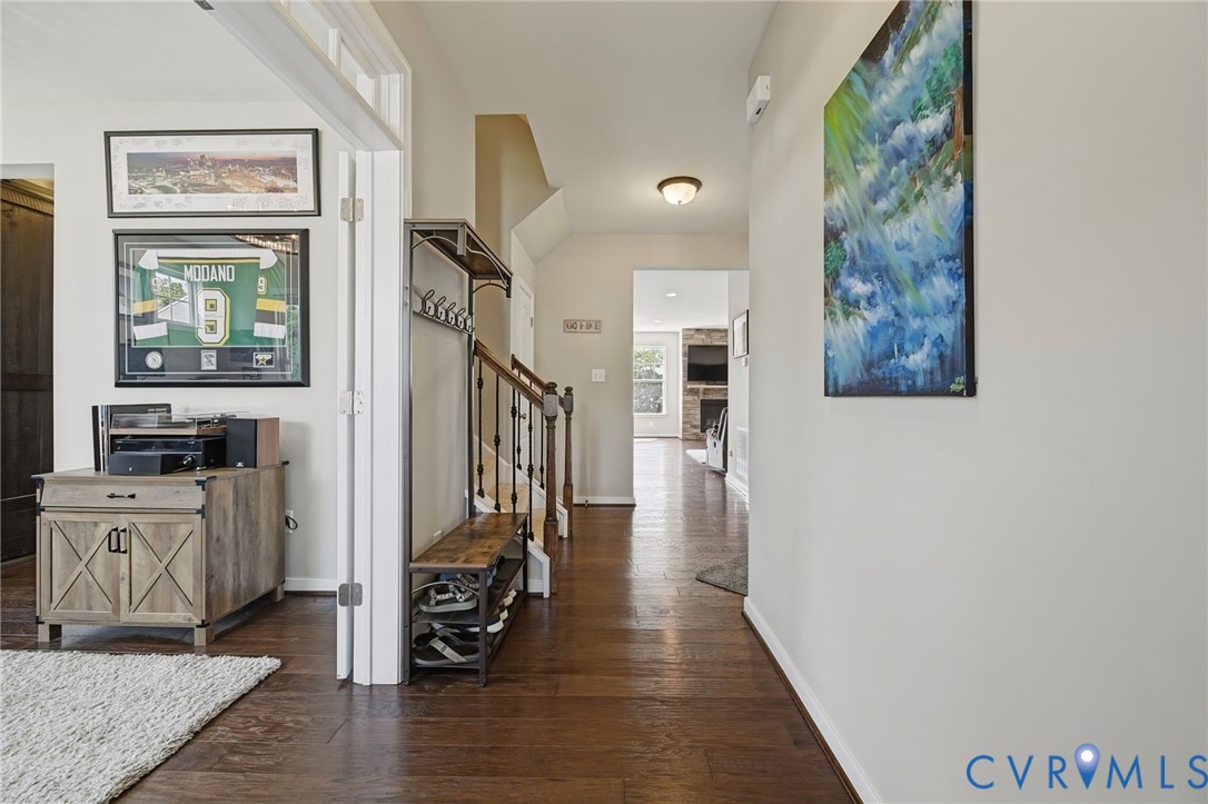 Entryway featuring dark wood-finish flooring, staircase with ornate iron balusters, and recessed ceiling lighting Entryway featuring dark wood-finish flooring, staircase with ornate iron balusters, and recessed ceiling lighting