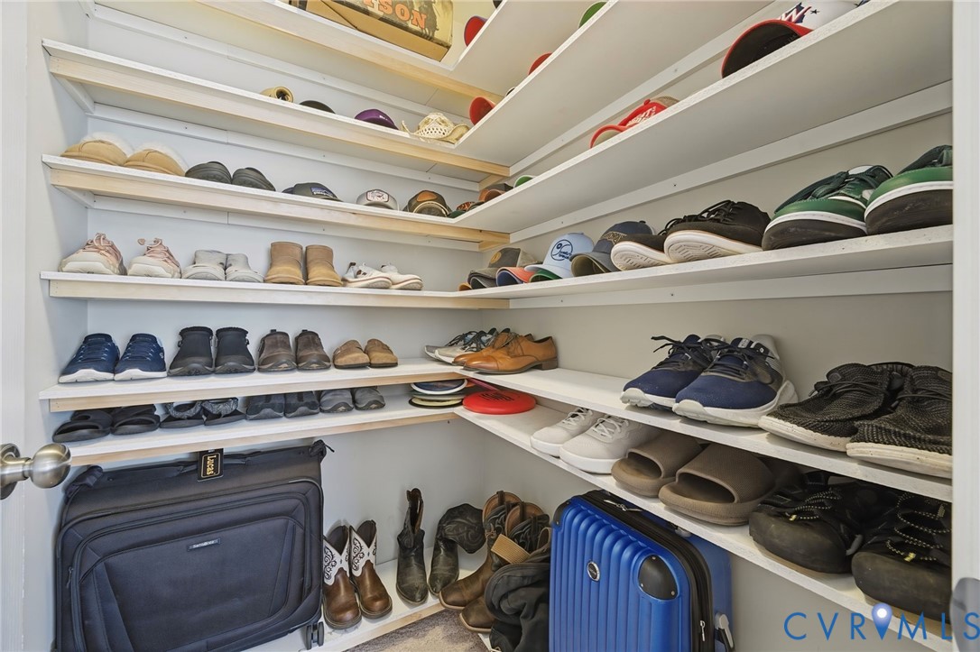 Custom closet featuring tiered, white-painted wooden shelving with corner-cut design and white walls