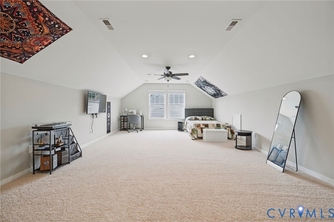 Expansive interior space featuring vaulted ceilings, neutral wall tones, wall-to-wall carpeting, recessed lighting, and a centrally mounted ceiling fan