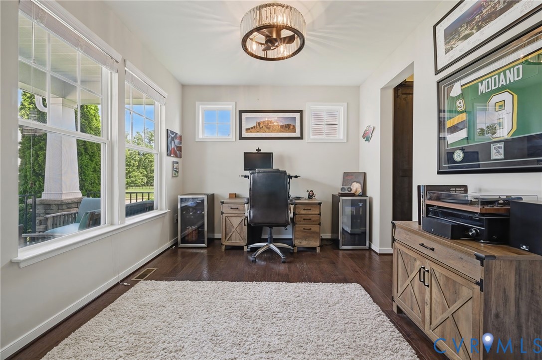 Room featuring wood-finish flooring, large double-pane windows, decorative ceiling fixture with integrated fan, and multiple wall-mounted windows Room featuring wood-finish flooring, large double-pane windows, decorative ceiling fixture with integrated fan, and multiple wall-mounted windows