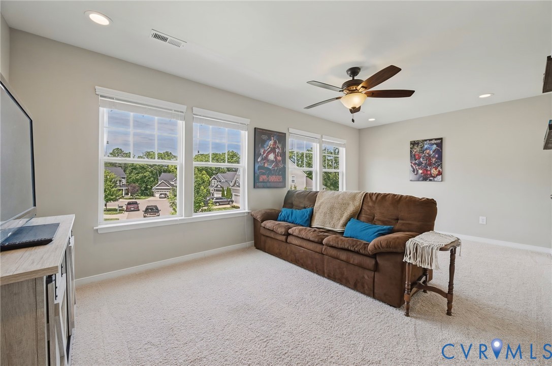 Neutral interior featuring wall-to-wall carpeting, recessed lighting, a multi-blade ceiling fan with integrated lighting, and multiple multi-pane windows