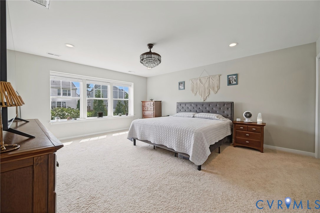 Spacious room featuring neutral carpeting, recessed lighting, a multi-pane window configuration, and a tiered glass-encased ceiling fixture