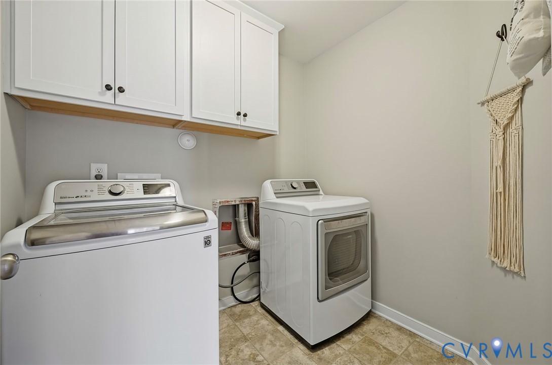 Laundry area featuring white shaker-style wall cabinetry and tile flooring