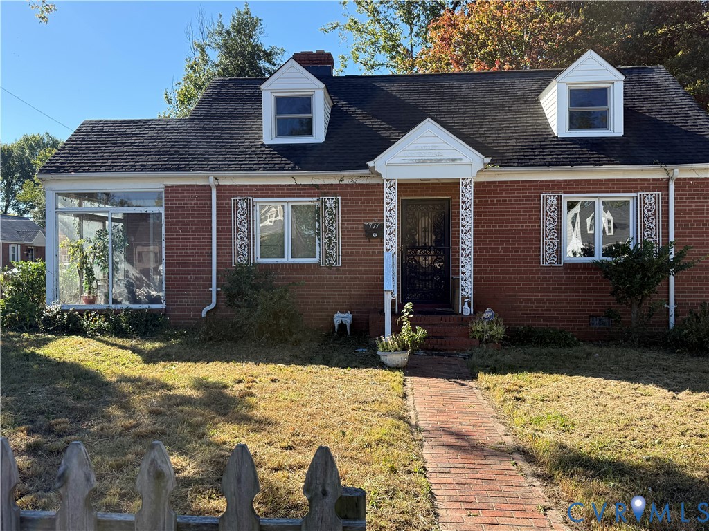 Cape Cod-style residence featuring a red brick exterior, two dormer windows, a covered front entryway with decorative metal supports, and a brick walkway Cape Cod-style residence featuring a red brick exterior, two dormer windows, a covered front entryway with decorative metal supports, and a brick walkway