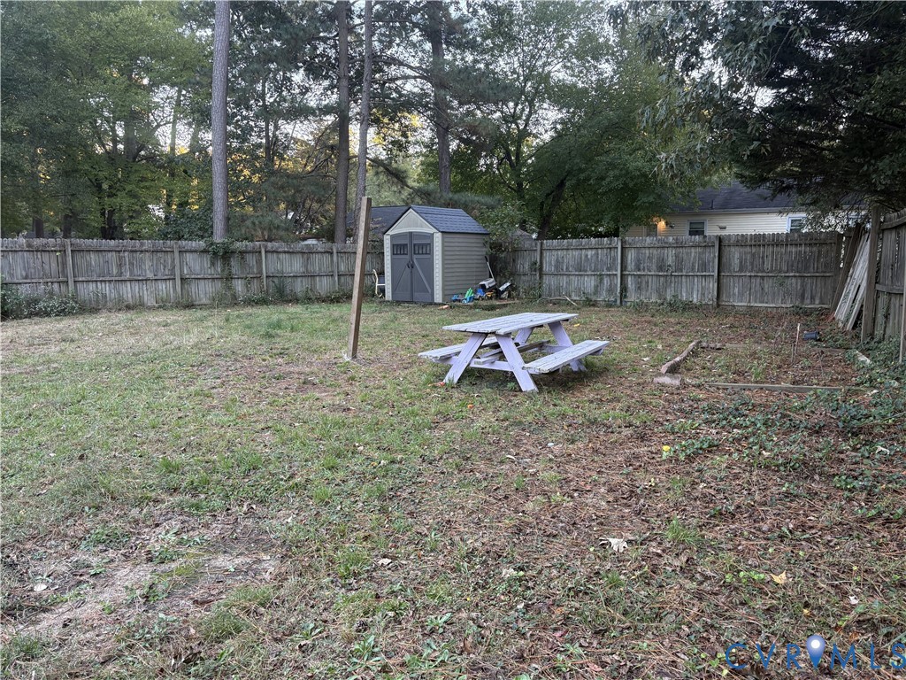 Backyard featuring a wood-panel fence, mature trees, and a detached storage structure