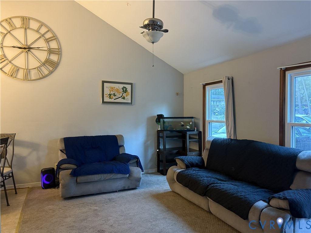 Vaulted ceiling featuring a central brushed-nickel ceiling fan with integrated light fixture and dual windows with wooden trim