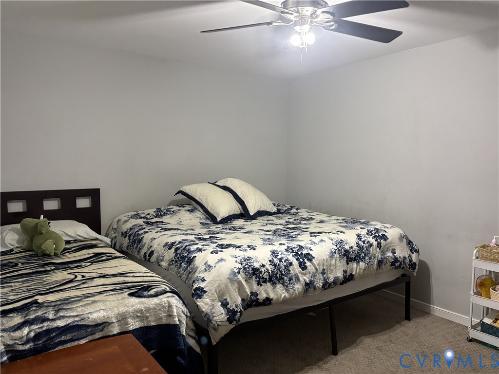 Neutral-toned interior space featuring a ceiling fan with integrated light fixture and wall-to-wall carpeting