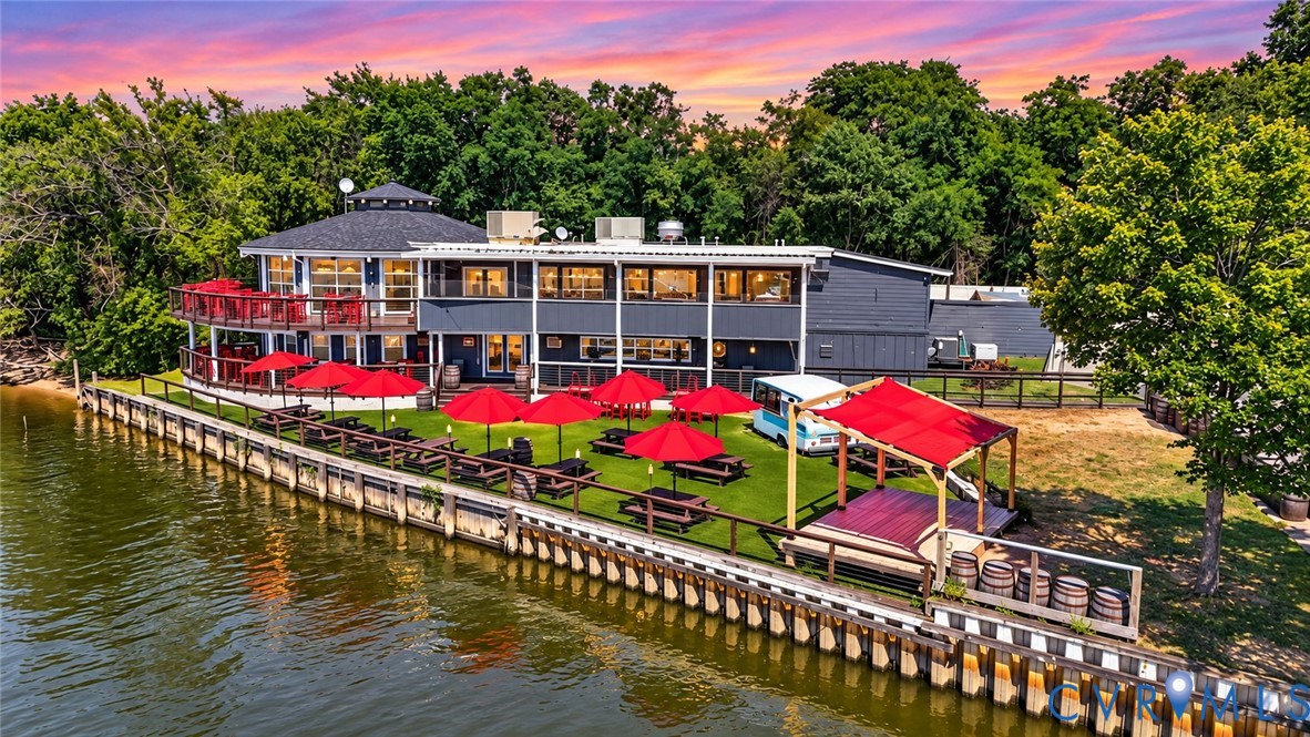 Waterfront structure featuring a multi-level deck, wood-bulkhead shoreline, expansive artificial turf lawn, and a covered outdoor platform