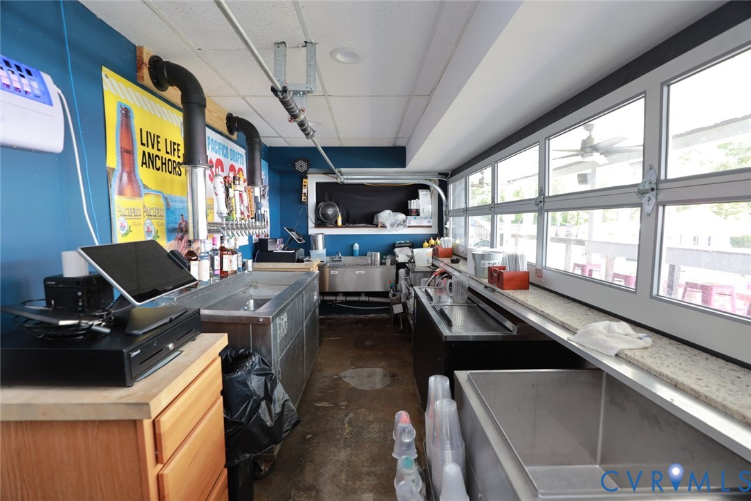 Service station featuring stainless steel multi-compartment sinks, expansive multi-pane windows with horizontal tracks, multi-tap beer dispensing system, and heavy-duty industrial flooring