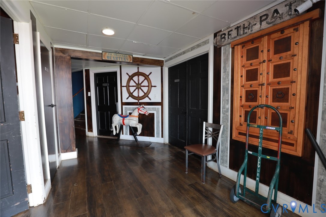 Hallway featuring dark wood-finish flooring, recessed ceiling lighting, decorative timber wall paneling, and custom carved wooden wall accents