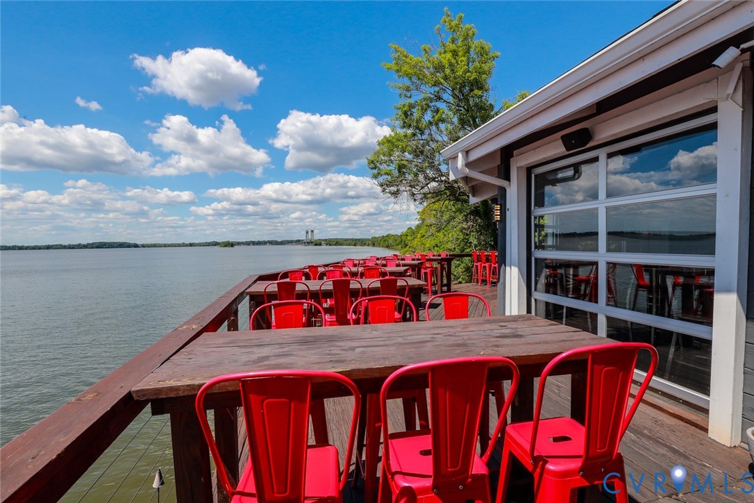Waterfront deck featuring wood-plank flooring, a wood railing, and a multi-paneled garage-style door system