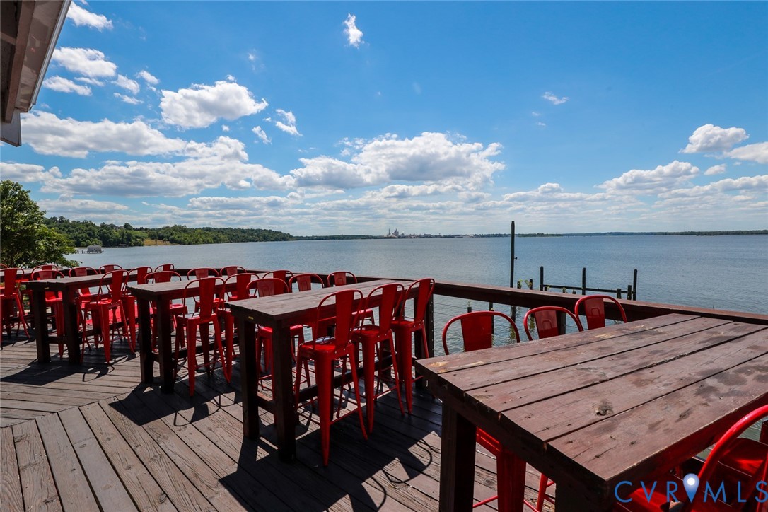 Elevated wooden deck featuring a horizontal railing and direct water frontage