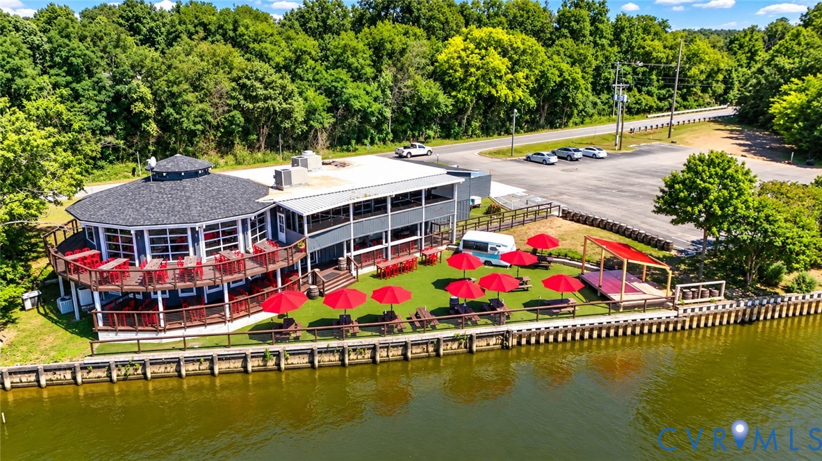 Waterfront property featuring a multi-level deck, shingle roof, paved surface parking, and a bulkhead Waterfront property featuring a multi-level deck, shingle roof, paved surface parking, and a bulkhead