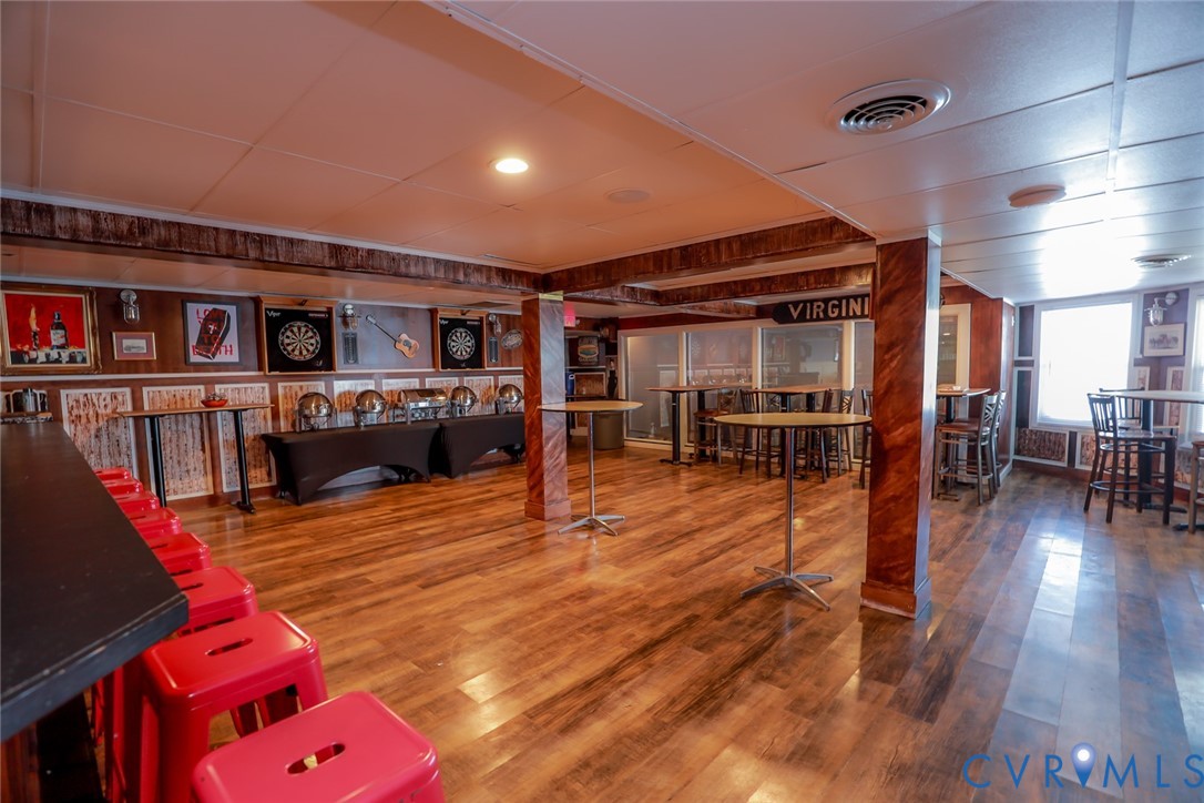 Finished lower level featuring wood-finish flooring, wood-paneled walls, and decorative columns with a faux wood grain finish