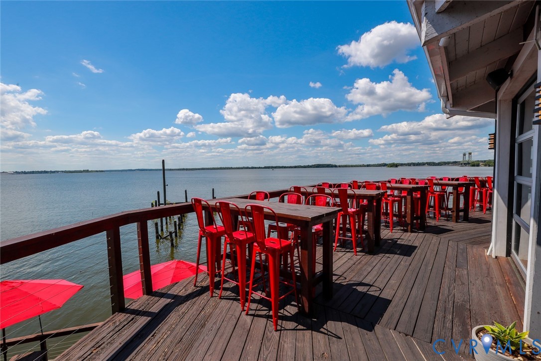 Expansive elevated wooden deck featuring cable railing and water-front positioning